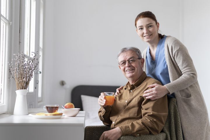 Liebenswürdige Krankenpflegerin umsorgt älteren Patienten